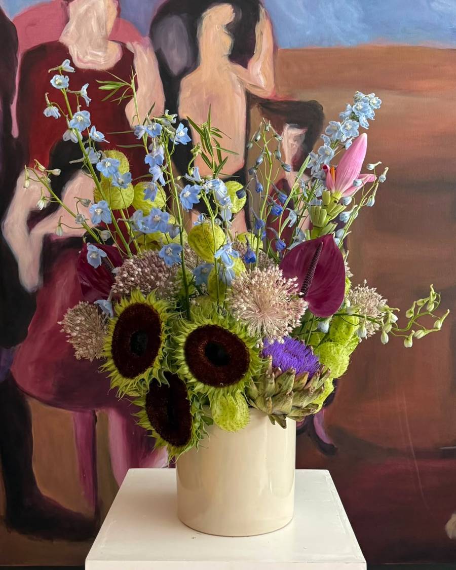 Arreglo con delphinium, girasol oscuro y alcachofa