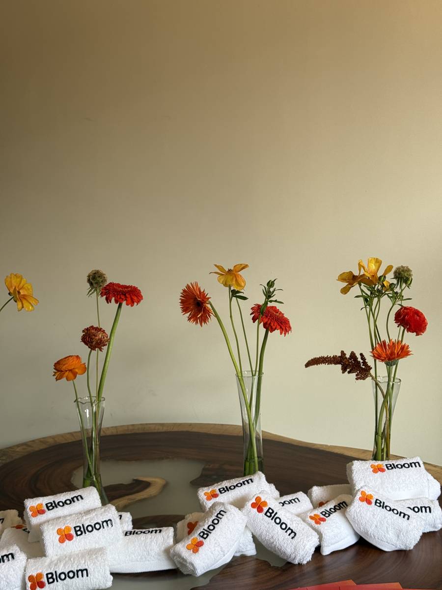 Vasos con flores junto a toallas con logo Bloom