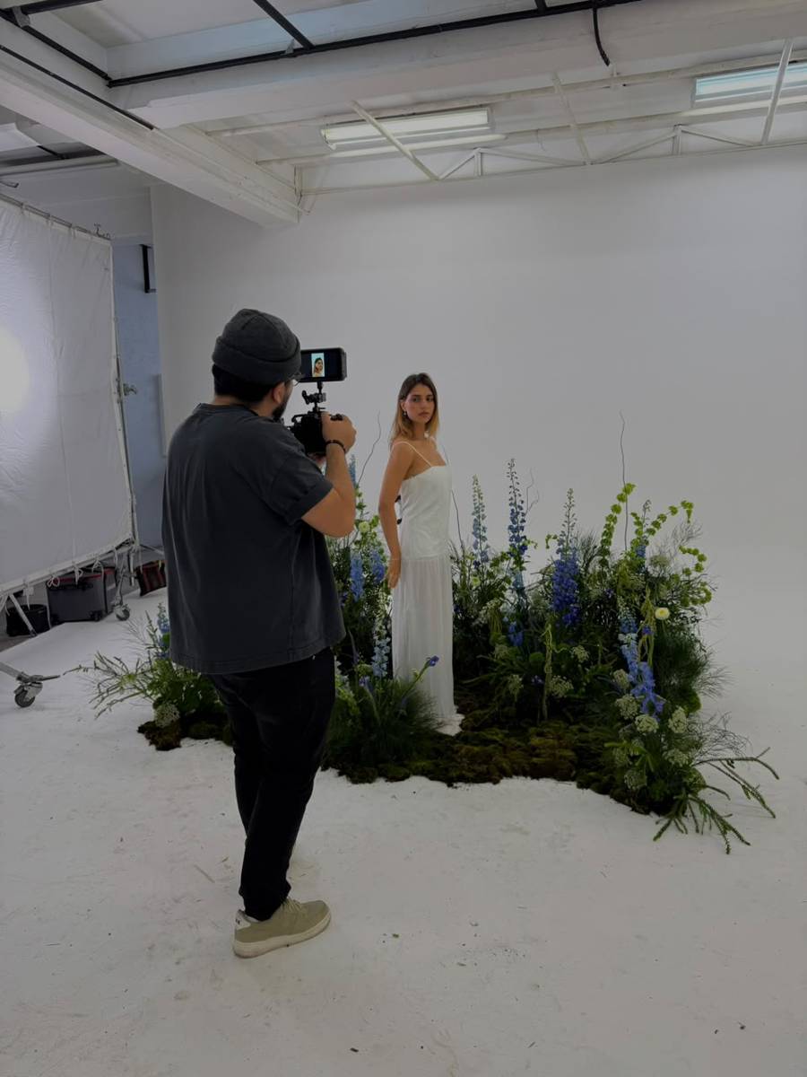 Fotógrafo tomando foto a modelo con instalación de delphinium azul