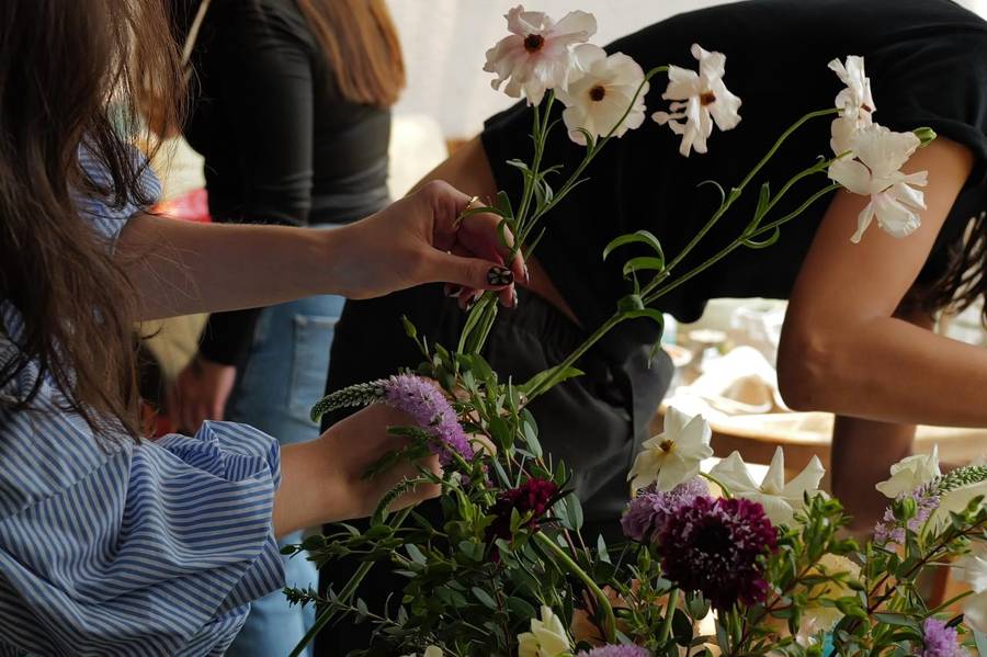 Manos colocando flores blancas en un arreglo